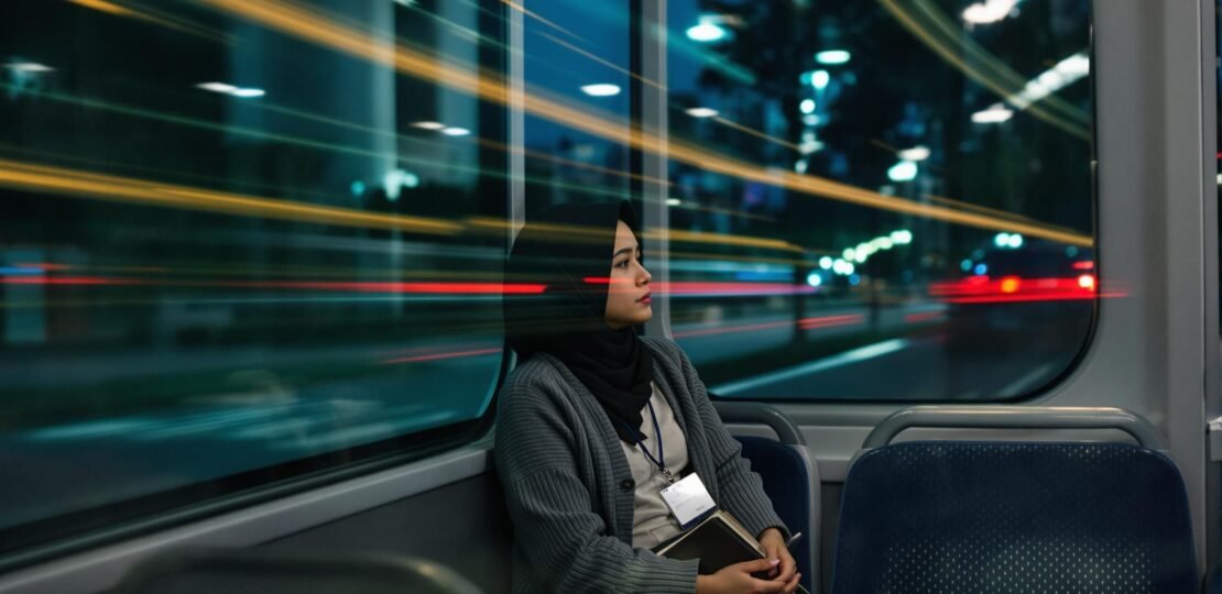 wanita muda Indonesia duduk di dalam kendaraan umum sambil menatap kosong ke luar jendela, menggambarkan hidup yang tampak stabil tapi terasa kosong di dalam.