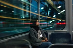 wanita muda Indonesia duduk di dalam kendaraan umum sambil menatap kosong ke luar jendela, menggambarkan hidup yang tampak stabil tapi terasa kosong di dalam.